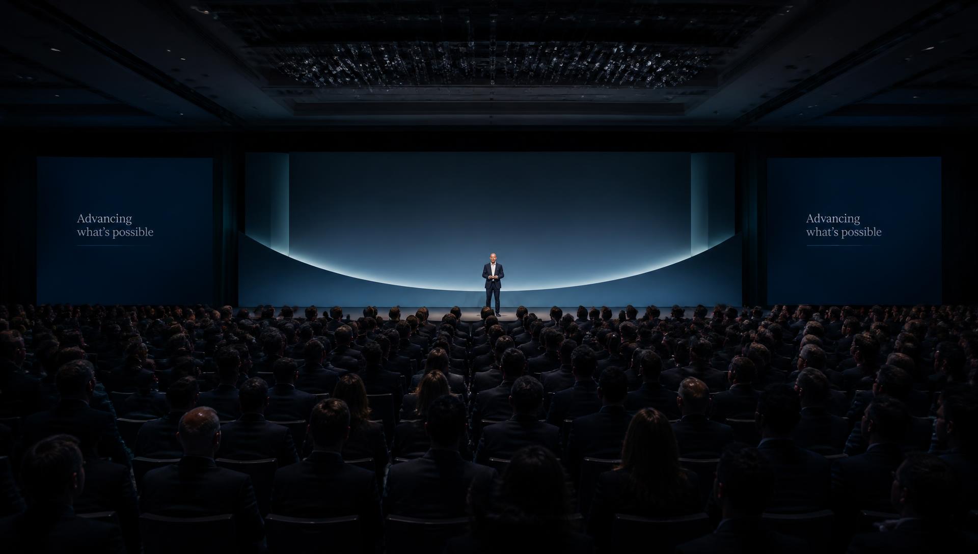 Executive audience at a corporate general session facing a softly lit keynote stage
